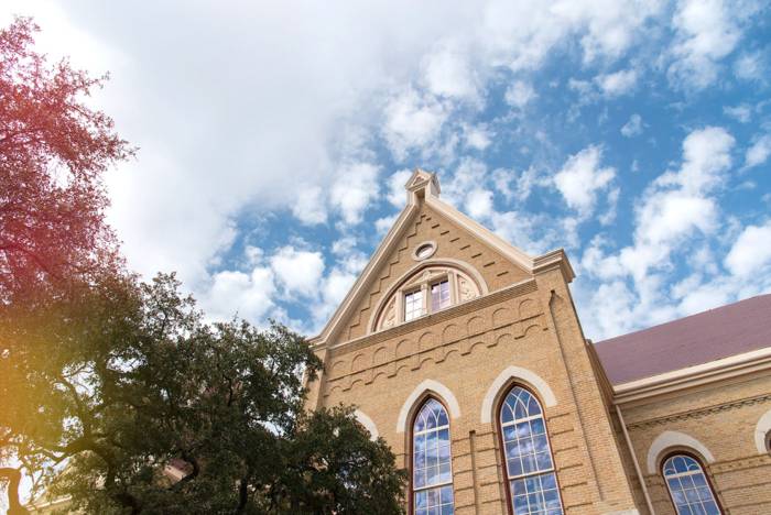 Old Main building from a dramatic angle with a blue sky and clouds above.